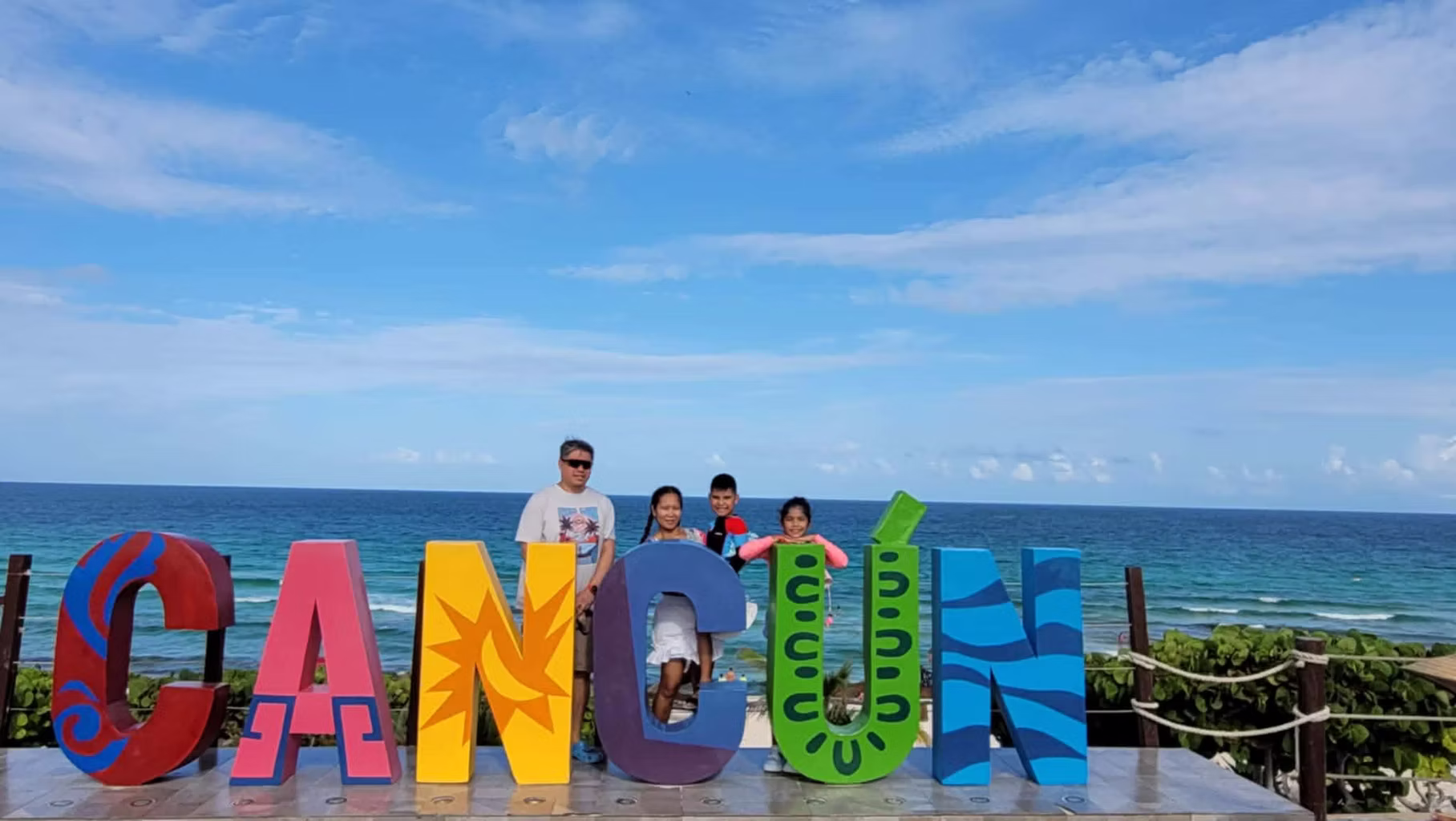 A family at the Cancún sign by the beach
