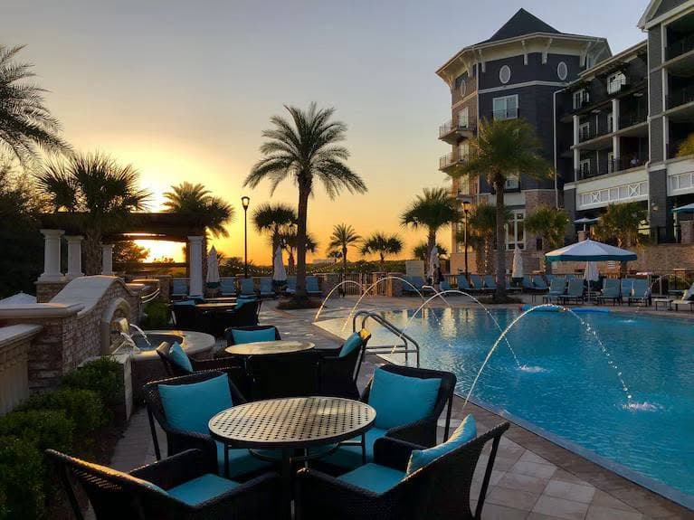 A resort pool surrounded by palm trees at sunset