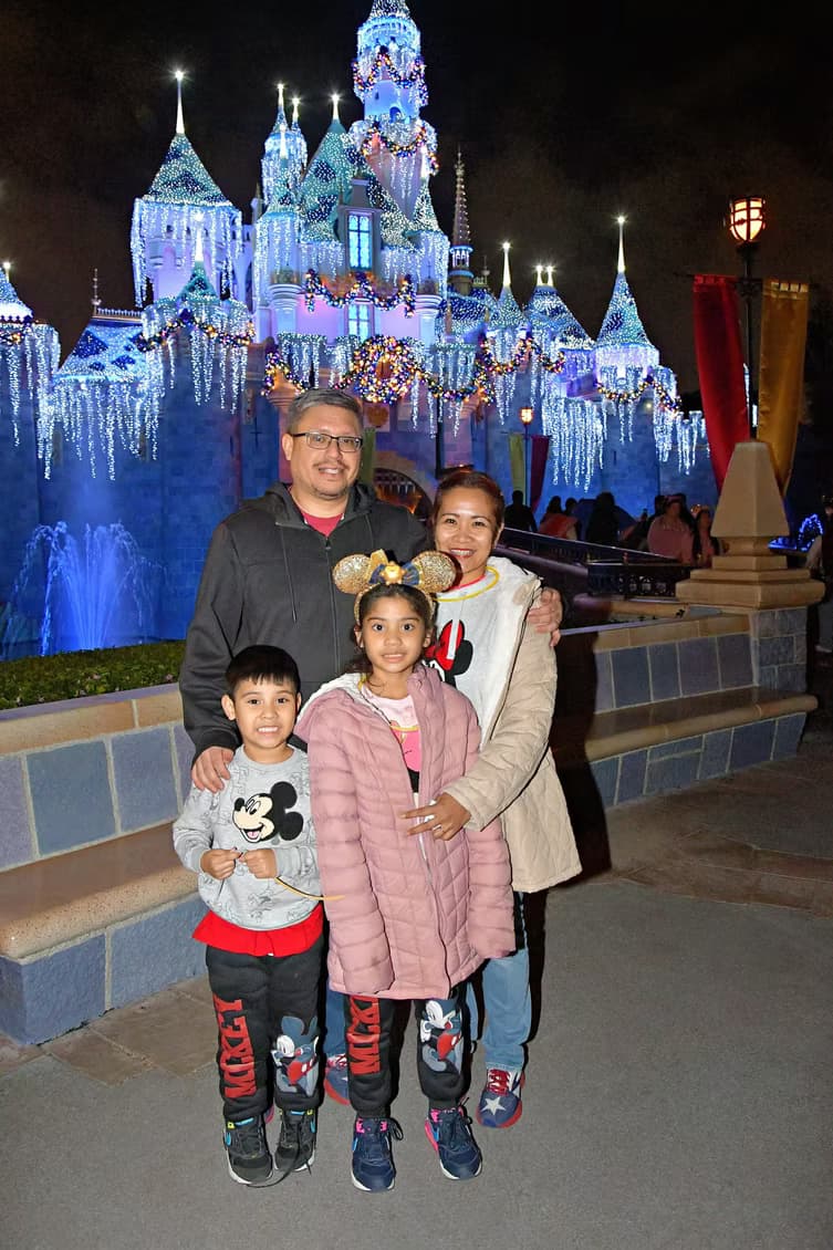 Canyesa and her family in front of the Disneyland castle at night