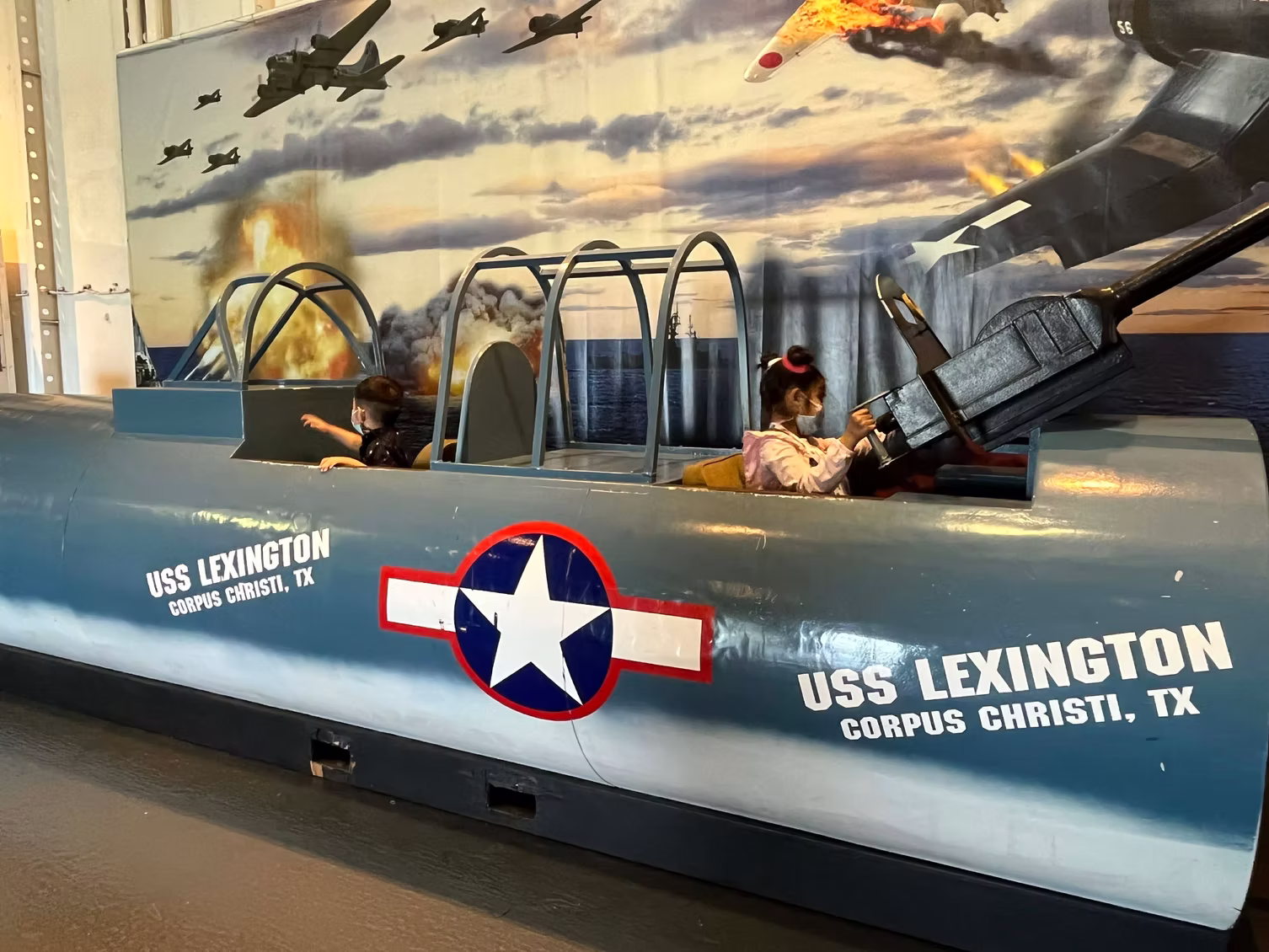 The kids in a vintage aircraft cockpit at the USS Lexington museum